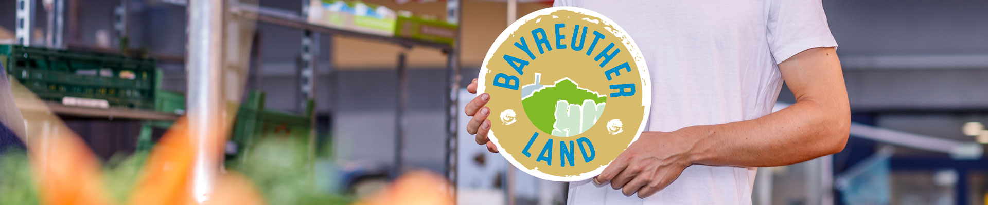 Junger Mann hält "Bayreuther Land Logo" in den Händen.