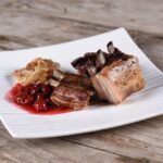 Wildschweinbraten auf Teller mit Preiselbeeren